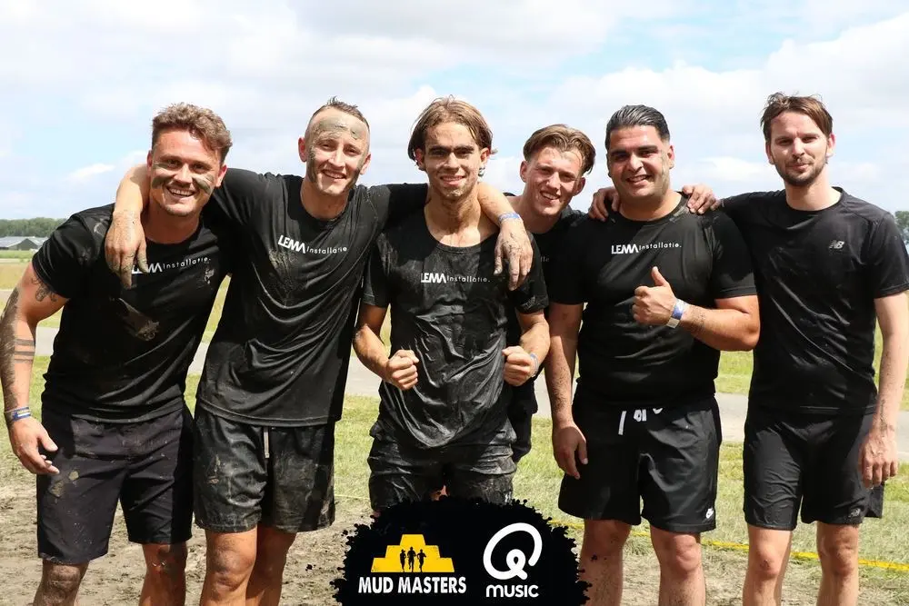 Zes teamleden van LEMA Installatie na afloop van een obstakelloop, onder de modder, in shirts met het woordmerk.